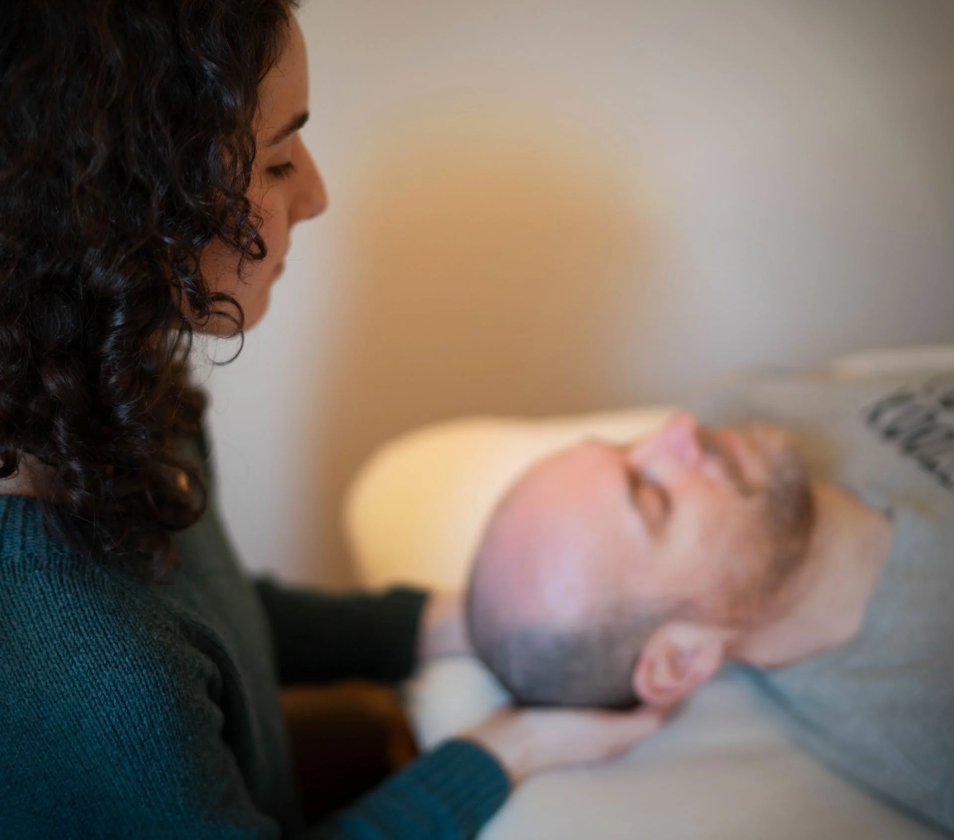 Vanessa seated at the head of the treatment table, holding a client's head in her hands.