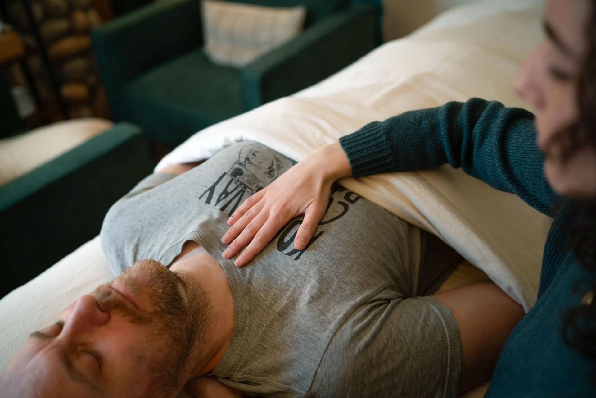 Vanessa resting a hand on a client's chest during a craniosacral session, the client lying on the treatment table with eyes closed.