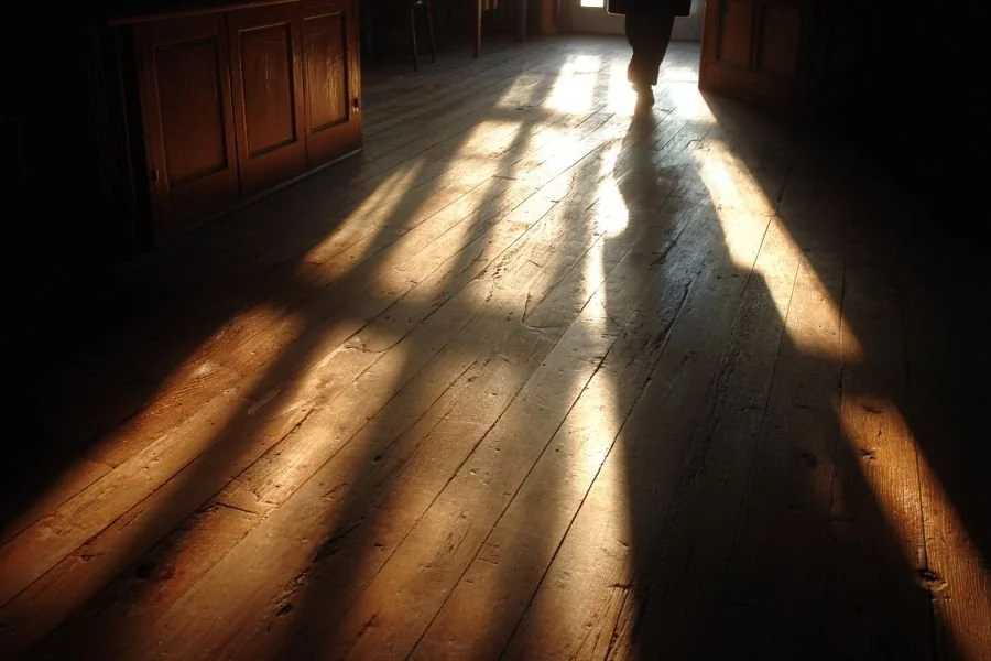 Shadow cast across wooden floor showing mindful movement, representing how the body holds and remembers experiences in somatic therapy