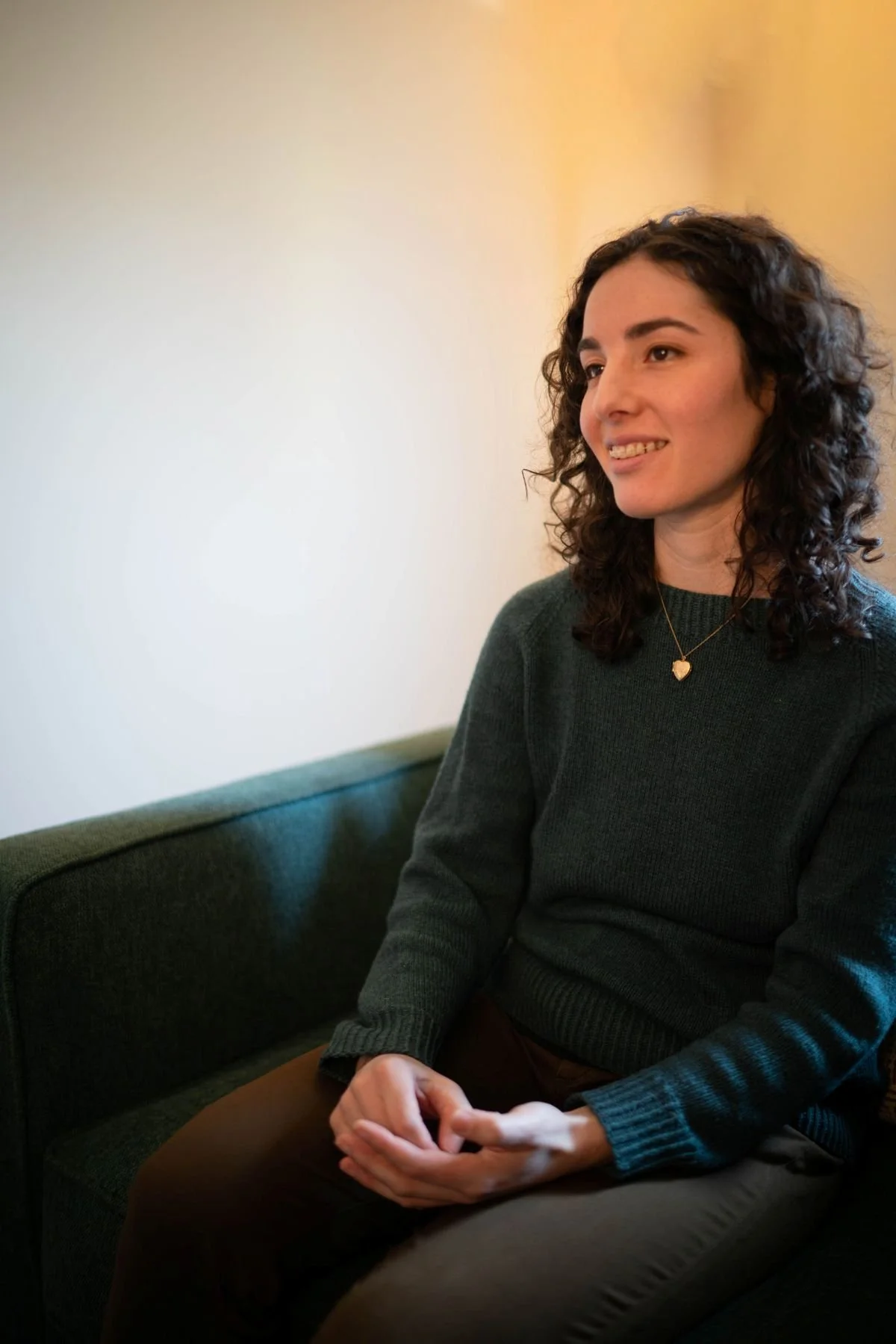 Vanessa smiling and listening, seated in a green armchair in her office.
